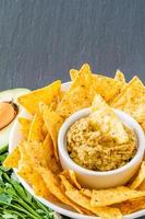 salsa di guacamole e ingredienti, nacho chips in una ciotola bianca foto