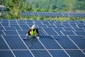 pulizia dei pannelli solari da parte dei lavoratori in sicurezza uniforme presso la fattoria solare foto