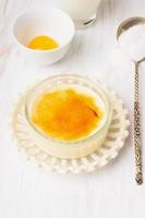 Crème brulée in ciotola di vetro sul tavolo di legno bianco foto