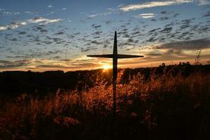 sagoma della croce cristiana sullo sfondo del tramonto foto