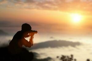 sagoma del fotografo che fotografa un tramonto in montagna. foto