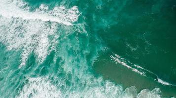 onde di texture vista dall'alto, schiuma e schizzi nell'oceano, giornata di sole foto