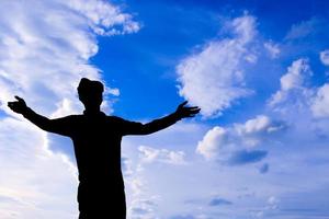 silhouette uomo in piedi spalancare le braccia sullo sfondo del cielo foto
