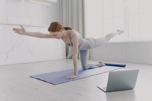 giovane donna che si gode lo yoga con lezioni video. esercizio mattutino e concetto di routine sportiva. foto