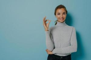 la foto di una bella giovane modella femminile con un trucco minimo i capelli pettinati sorride mostra delicatamente un gesto ok