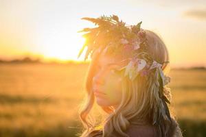 ritratti di giovane donna che si diverte nel campo di grano durante il tramonto, signora in testa corona di fiori durante foto