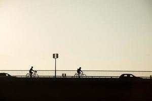 silhouette bicicletta del ciclista sul ponte contro il tramonto, paesaggio urbano minimalista foto