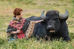 giovane donna vestita con un poncho giro su un grande bufalo d'acqua foto