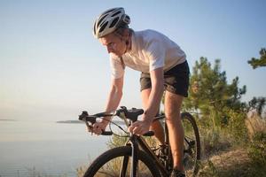 ciclista su ciclocross professionale in bicicletta in discesa, pino e sfondo del lago foto