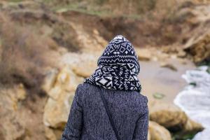 giovane donna in cappotto grigio sullo sfondo del mare autunnale foto