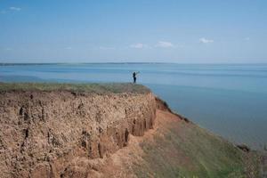 paesaggio minimalista con scogliere di argilla e mare e giovane escursionista foto