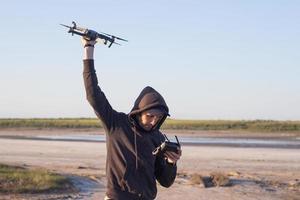 immagine di drone quadricottero nero e siluette pilota su sfondo chiaro del tramonto, uso turistico dron elicottero per fotografie o riprese di paesaggi desertici