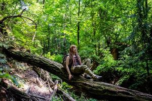 giovane donna che fa un'escursione sul prato di primavera, sulle montagne e sulla foresta sullo sfondo foto