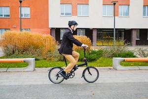 giovane uomo d'affari maschio con bicicletta e tazza di caffè o tè che cammina all'aperto foto