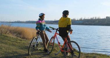 coppia di uomini e donne in bicicletta vicino al fiume durante il tramonto foto