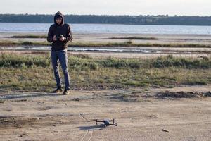 immagine di drone quadricottero nero e siluette pilota su sfondo chiaro del tramonto, uso turistico dron elicottero per fotografie o riprese di paesaggi desertici