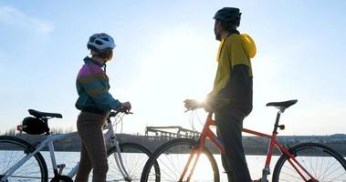 coppia di uomini e donne in bicicletta vicino al fiume durante il tramonto foto