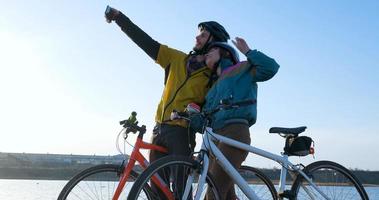 coppia di uomini e donne in bicicletta vicino al fiume durante il tramonto foto