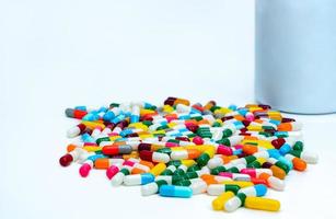 capsule colorate vicino al flacone di plastica per farmaci. pillole multicolori della capsula sul tavolo bianco. prodotti della farmacia della farmacia. industria farmaceutica. bilancio e politica sanitaria. pillole della capsula di colori brillanti foto