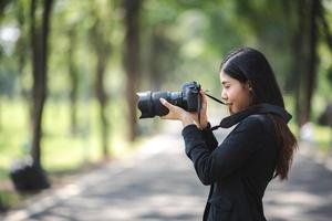 giovane donna asiatica del fotografo con la ripresa della fotocamera digitale ad alta tecnologia foto