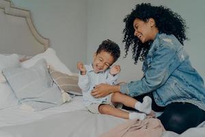 donna afroamericana che si diverte con il piccolo adorabile figlio a casa foto