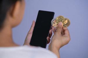 moneta golden bitcoin dogecoin doge, gruppo ethereum eth incluso con criptovaluta a portata di mano donna o ragazza e smartphone cellulare archiviato mettere e dare sfondo viola. concetto di acquisto online. foto