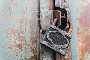 lucchetto arrugginito chiude a chiave il vecchio cancello di un hangar abbandonato foto