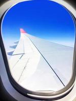 vista di un aereo commerciale dalla finestra dove si può vedere l'ala che vola sopra le nuvole ad un'altezza di 35.000 piedi. foto