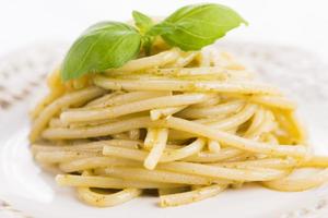spaghetti italiani con pesto e foglia di basilico foto
