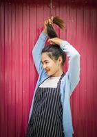 una giovane donna in piedi con i capelli sorridenti, affascinante, vicino al muro di zinco rosa. foto