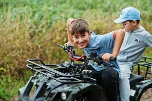 due fratelli che guidano un quad quad a quattro ruote. momenti felici dei bambini. foto