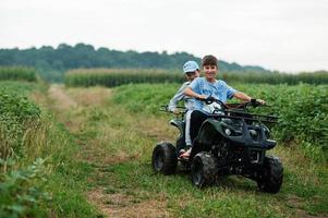 due fratelli che guidano un quad quad a quattro ruote. momenti felici dei bambini. foto