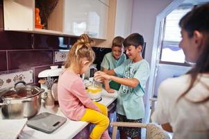 madre con bambini che cucinano in cucina, momenti felici per bambini. foto