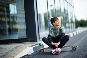 ragazzo adolescente in una tuta sportiva con longboard. foto