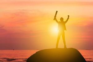 silhouette di uomo d'affari celebrazione successo felicità su una cima di una montagna tramonto sera cielo sfondo, sport e concetto di vita attiva foto