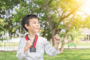 bambino felice del taekwondo che posa nell'azione di combattimento sulla natura al parco foto