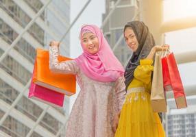 ritratto di felice bella giovane donna araba d'affari con borse della spesa, felice shopping nel concetto di città foto