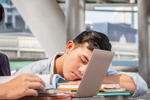 giovane studente di college asiatico che dorme dopo aver letto un libro, giovani studenti esausti che si addormentano, concetti di istruzione foto