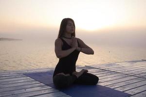 giovane donna in posa in asans yoga, sfondo del mare mattutino foto