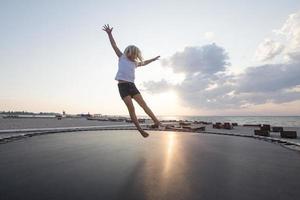 la bambina salta e si diverte sul trampolino in estate foto