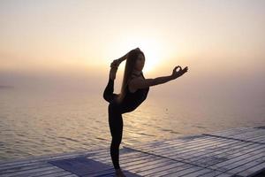 giovane donna in posa in asans yoga, sfondo del mare mattutino foto