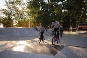 gruppo di giovani con biciclette bmx in skate plaza, ciclisti acrobatici nello skatepark foto