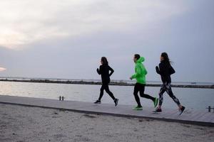 gruppo di giovani che si allenano all'aperto, esercizi di corridori, sfondo di mare o fiume foto