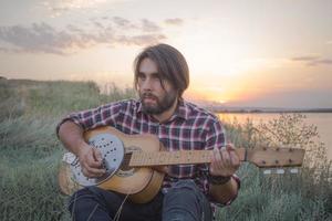 giovane maschio con la chitarra acustica all'aperto foto