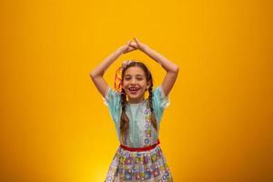 bambino in abiti tipici della famosa festa brasiliana chiamata festa junina nella celebrazione di sao joao. bella ragazza su sfondo giallo. foto