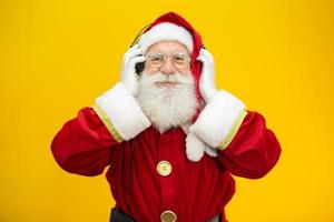 Babbo Natale che balla su sfondo giallo. babbo natale che indossa le cuffie. concetto di festa di natale con musica. foto