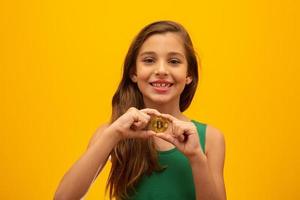 bambino che tiene criptovaluta in metallo. moneta d'oro. d'oro. su sfondo giallo. foto