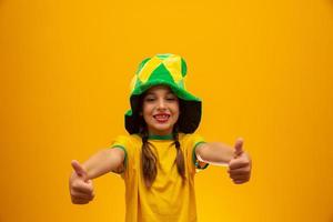 tifoso di calcio, squadra del Brasile. Coppa del Mondo. bella bambina tifo per la sua squadra su sfondo giallo foto