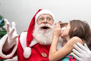 bambina che sussurra all'orecchio di Babbo Natale. raccontare un segreto. rivelando il regalo che vorresti vincere. parlando di come si è comportata durante l'anno. foto