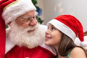 Babbo Natale consegna una confezione regalo a una bambina. vigilia di natale, consegna di regali. foto